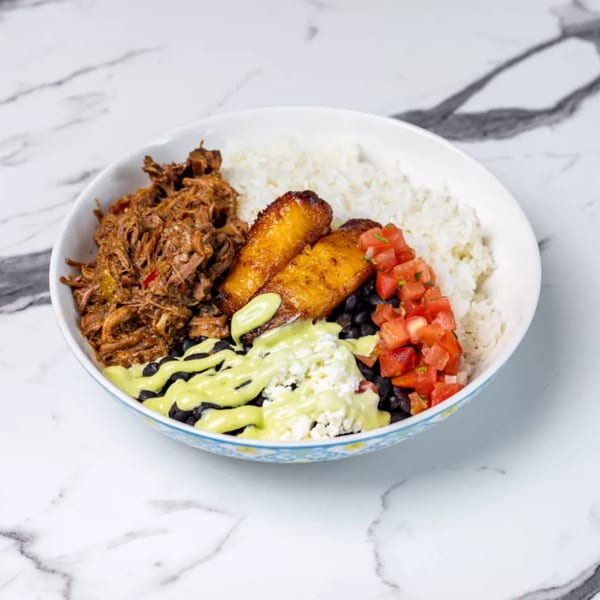Cuban bowl with shredded beef, rice, black beans, plantains, pico de gallo, cheese, and green sauce.