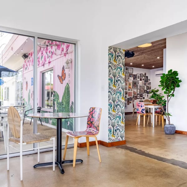 Bilia Eatery's vibrant interior with patterned chairs, a gallery wall, and a pink exterior mural.