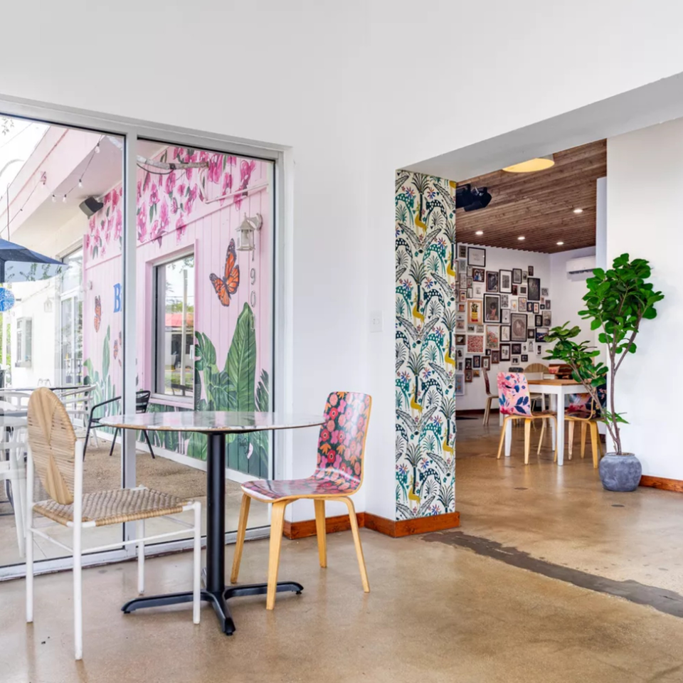 Bilia Eatery's vibrant interior with patterned chairs, a gallery wall, and a pink exterior mural.