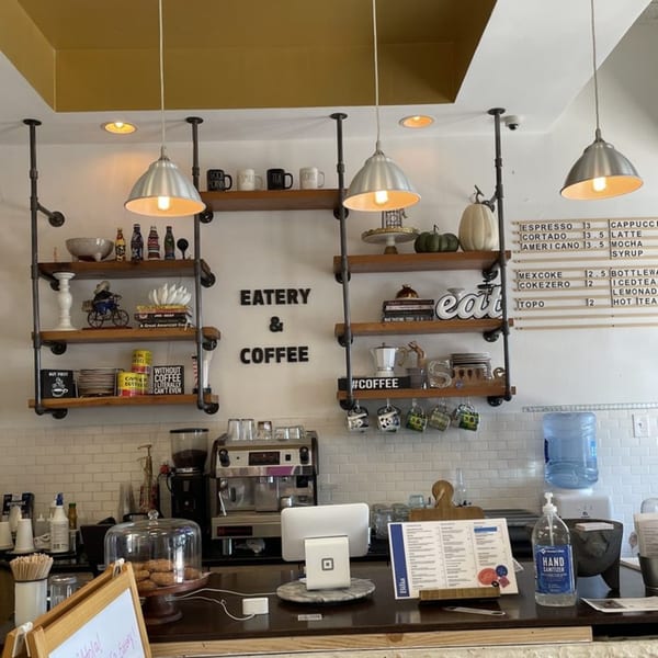 Interior of Bilia Eatery, showing a coffee bar with shelves, drinks menu, and baked goods.